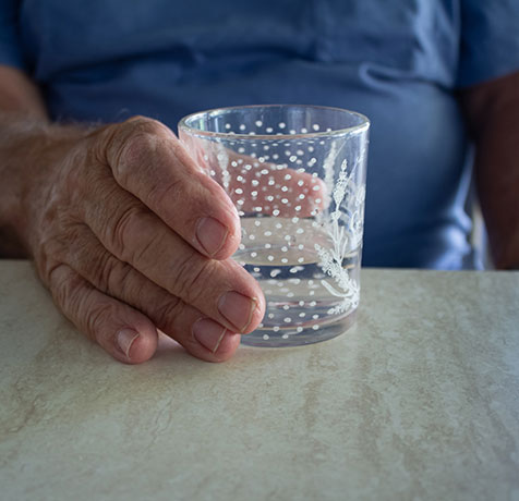 Hand holding a glass of water on a table